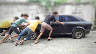 A group of men pushing a car with flat tires